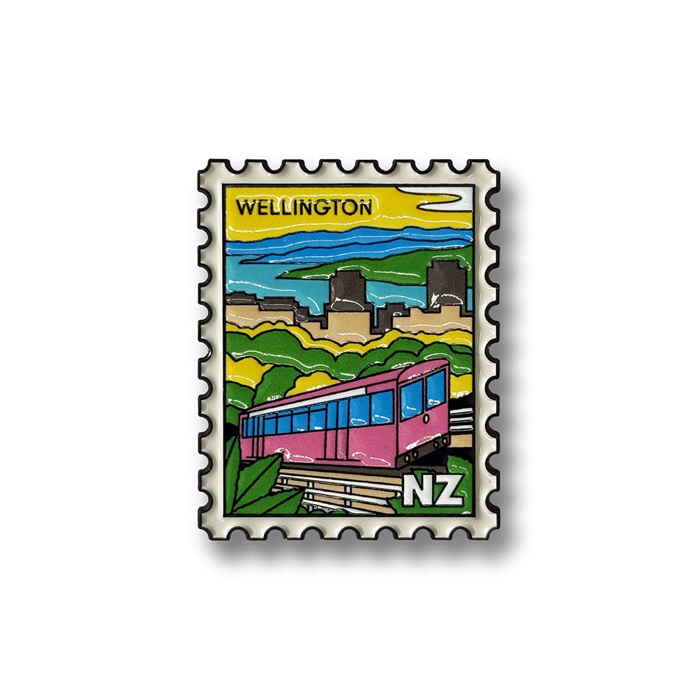A stylized postage stamp illustration features a pink Wellington Cable Car in the foreground with “WELLINGTON” at the top, city buildings, green hills, and a blue sky in the background. "NZ" appears in the lower right corner, making this Wellington Cable Car Collectible Stamp Magnet a charming tribute to New Zealand’s vibrant capital.
