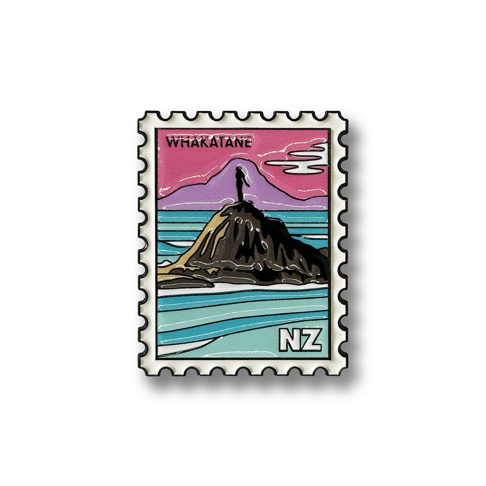 Introducing the Whakatane Collectible Stamp Magnet: a vibrant enamel magnet depicting a New Zealand postage stamp scene. It features a rocky island with a figure atop, set against a colorful sky and ocean, with the label "Whakatane" and NZ initials at the bottom right corner—making it a charming keepsake from New Zealand.