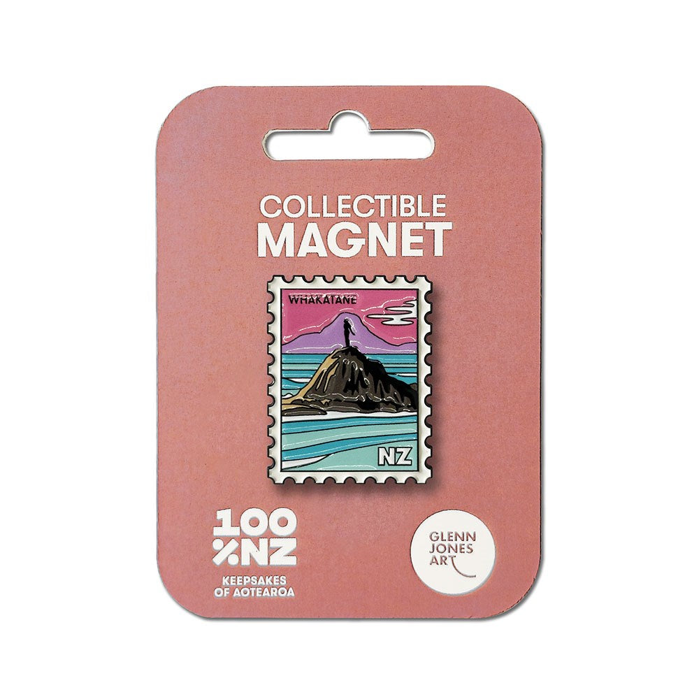The Whakatane Collectible Stamp Magnet is an enamel magnet shaped like a postage stamp, featuring an illustrated coastal scene of Whakatāne, New Zealand with a sunset sky and ocean waves. It comes on a pink backing card labeled “Collectible Magnet” at the top.