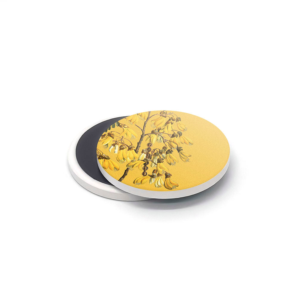 Two round pieces from the Vintage Botanical Ceramic Magnet Set are stacked slightly askew. The top magnet has a yellow background with a black and yellow botanical design, while the plain, dark magnet sits beneath on a white surface.