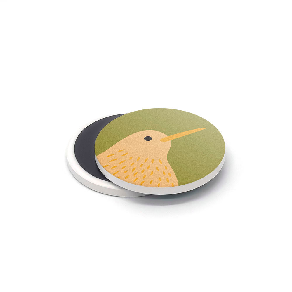 A Storybook Ceramic Magnet Set piece: a round magnet with a green background and an illustration of a yellow bird with orange beak and dotted markings, printed in New Zealand. A second plain magnet is partly visible underneath.