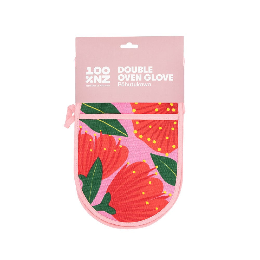 The Bright Botanical Pink Pohutukawa Double Oven Glove is made from 100% cotton, quilted for comfort, and features red pōhutukawa flowers with green leaves. It comes packaged with a pink label reading “100% NZ Double Oven Glove Pōhutukawa.”.