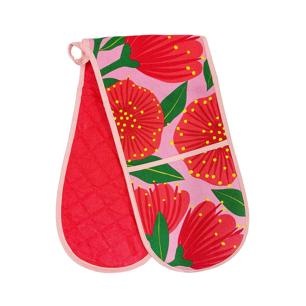 The Bright Botanical Pink Pohutukawa Double Oven Glove is made from 100% cotton, with a quilted red interior and a pink exterior featuring large red flowers, green leaves, yellow dots, and finished with light pink trim.