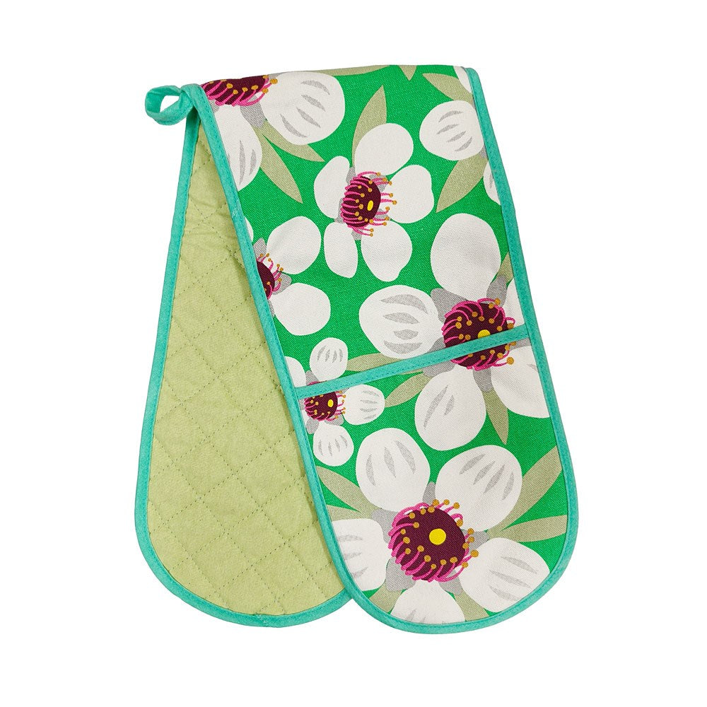 Part of the Bright Botanicals Range, the Bright Botanical Manuka Double Oven Glove is 100% cotton with a green background, white and purple flowers on one side, plain light green quilted reverse, and turquoise trim.