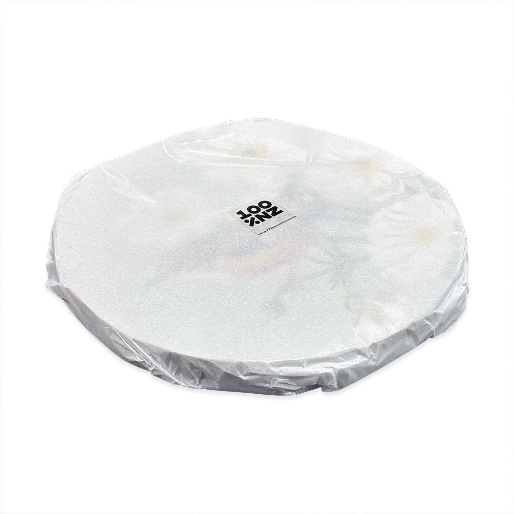 A round, cork-backed placemat from the Birds & Botanicals Placemats Set of 6, topped with a clear plastic layer and a central rectangular label with black text, featuring New Zealand birds and botanicals for added charm.