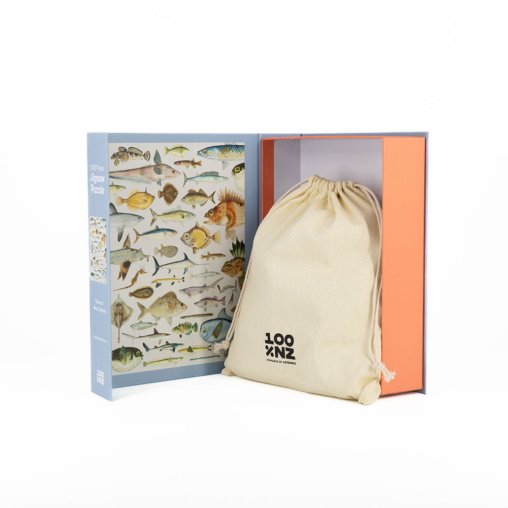 The Fishes of NZ Jigsaw Puzzle, featuring colorful marine life, is displayed next to a beige “LOOK” drawstring bag on a plain white background.