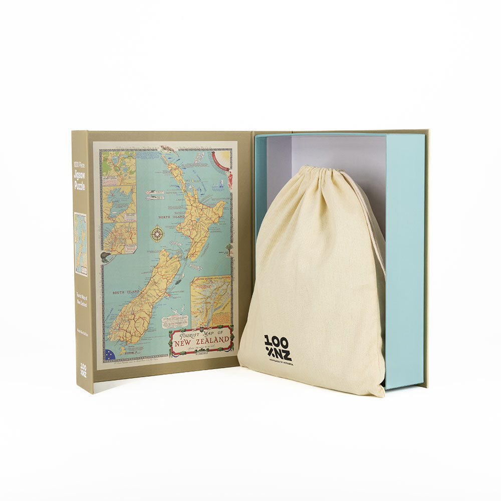 The Tourist Map of NZ Jigsaw Puzzle is a boxed 1000-piece set featuring a vintage New Zealand map, with pieces stored in a cream LOOZANO drawstring bag, displayed on a white background.