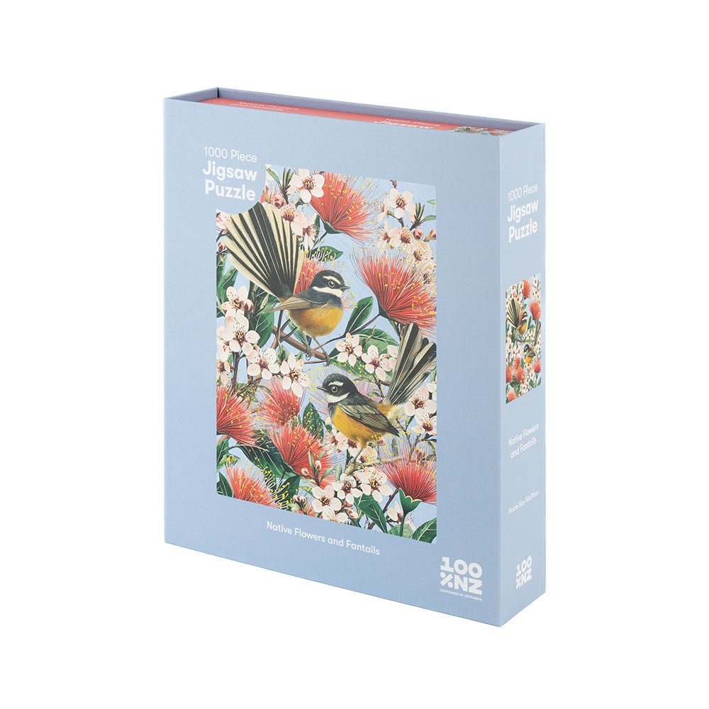 A blue box labeled Native Flowers and Chatty Fantails Jigsaw Puzzle Box contains a 1000-piece puzzle featuring two fantails among red and white New Zealand native flowers.