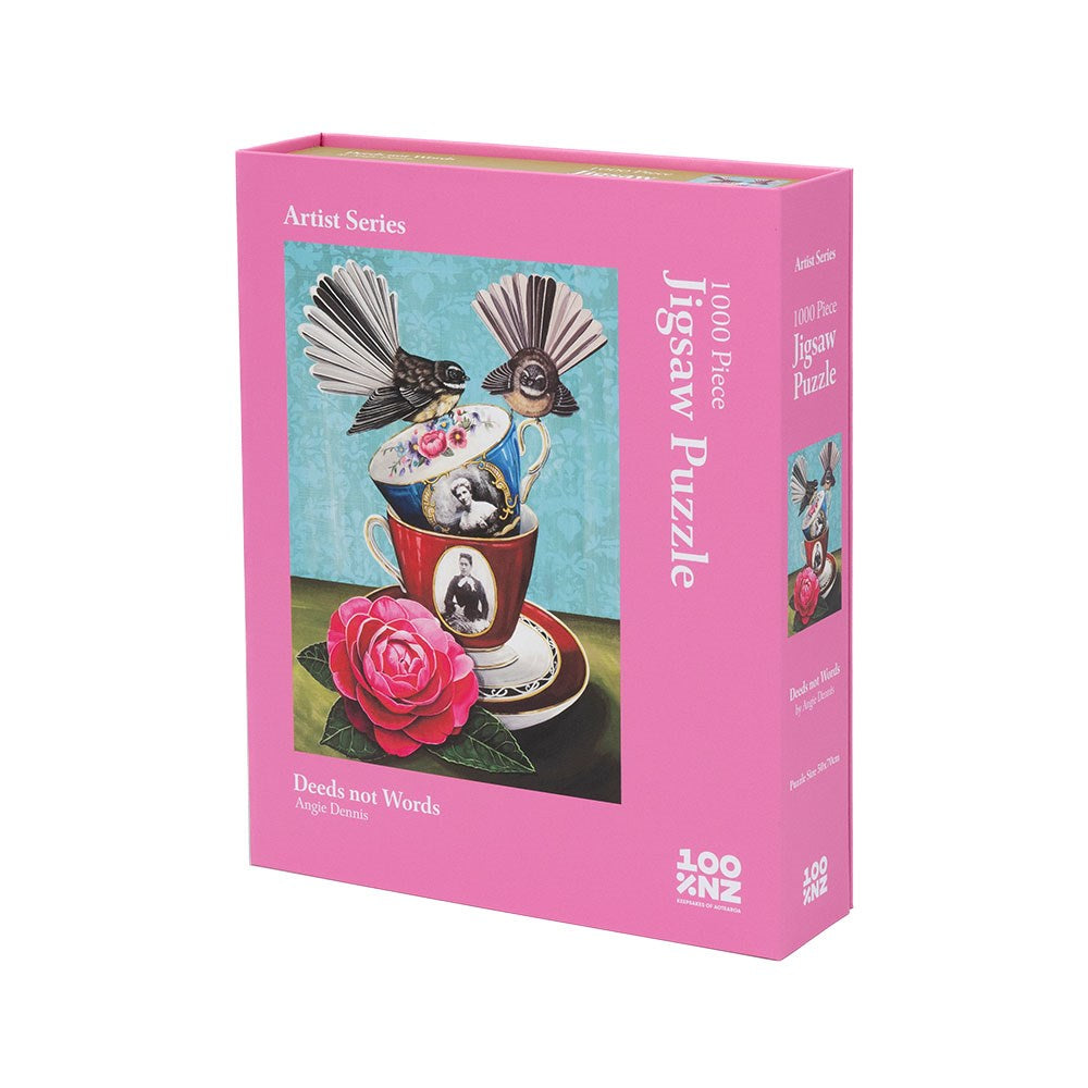 The Angie Dennis - Deeds not Words Jigsaw Puzzle is a 1000-piece, pink-box puzzle from New Zealand, featuring surreal art with birds, teacups, a butterfly, and a rose, celebrating the suffragette movement.