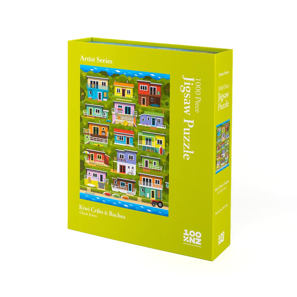 The Glenn Jones - Kiwi Cribs & Baches Jigsaw Puzzle is a 1000-piece Artist Series puzzle in a green box, featuring vibrant art of colorful coastal New Zealand houses.