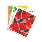 Three rectangular Swedish Dishcloths - Bright Botanicals with colorful floral designs—large red flowers, yellow dots, and green leaves on a pink background—overlapped and seen from above; an eco-friendly addition to your kitchen.