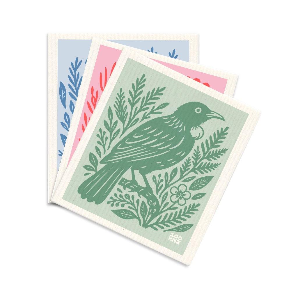 Three rectangular Swedish Dishcloths - NZ Woodcut Birds are stacked, the top one featuring a native bird with leaves and flowers on light green, with two below in blue and pink, all showcasing botanical, eco-friendly designs.