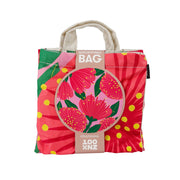 The Bright Pink Pohutukawa Shopping Bag is a foldable, affordable reusable bag with a vivid red, pink, yellow, and green floral design. The packaging says “SHOPPING BAG” and highlights a close-up illustration of the pohutukawa flower.