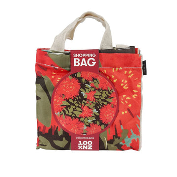 The Vintage Pohutukawa Shopping Bag is an affordable, lightweight folded fabric bag with handles, labeled “Shopping Bag” featuring a red floral design with green leaves and the word Pohutukawa at the bottom.