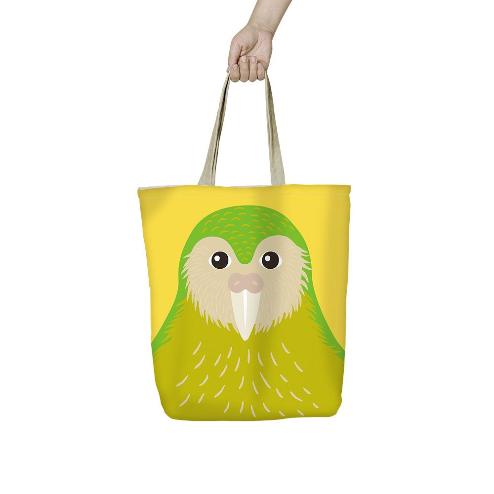 A hand holds the Bright Kakapo Shopping Bag, an affordable, lightweight yellow tote with tan straps, featuring a cartoon green and yellow kakapo—perfect as a reusable shopping bag.