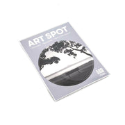 The Mission Bay Art Spot is a flat-laid package with a black-and-white landscape of trees and a bench. This repositionable wall art uses unique adhesive for easy peel, stick, remove, or reposition. Made in New Zealand.