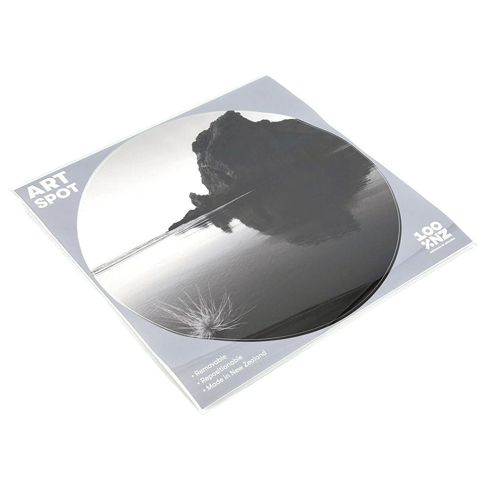 The Piha Art Spot comes in square packaging with a circular black and white photo of a rocky outcrop reflected in still water. It’s repositionable wall art, made in New Zealand, with unique adhesive.