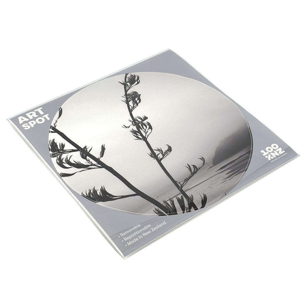 The Paihia Art Spot is a round matte fabric sticker featuring a black and white plant silhouette on a misty background, attached to a square backing labeled “ART Spot,” “Removable,” “Reusable,” and “Made in New Zealand.”.
