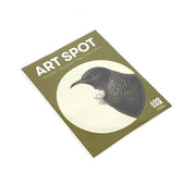 A postcard titled Hushed Green Tui Art Spot features a black bird with white throat feathers on a green background. Printed on matte fabric finish, it has 100 Years of Forest & Bird text at the bottom right.