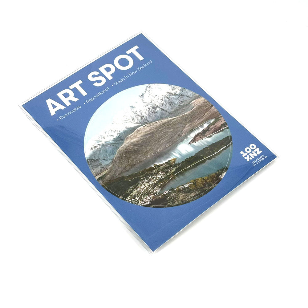 A rectangular blue package titled Queenstown Art Spot features a circular mountain landscape image, mentions Remarkable, Representation, Made in New Zealand, 100 PAK 4 PANEL, and has a matte fabric finish.