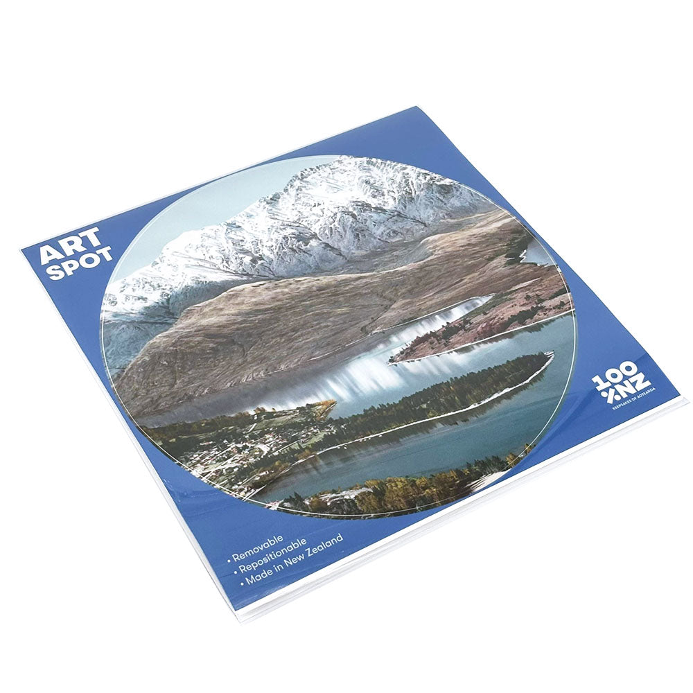 A square blue Queenstown Art Spot notepad features a circular lake and mountain photo, text reading ART SPOT and 100% NZ, highlights like Remarkable, Reusable, Made in New Zealand, and has a matte fabric finish.