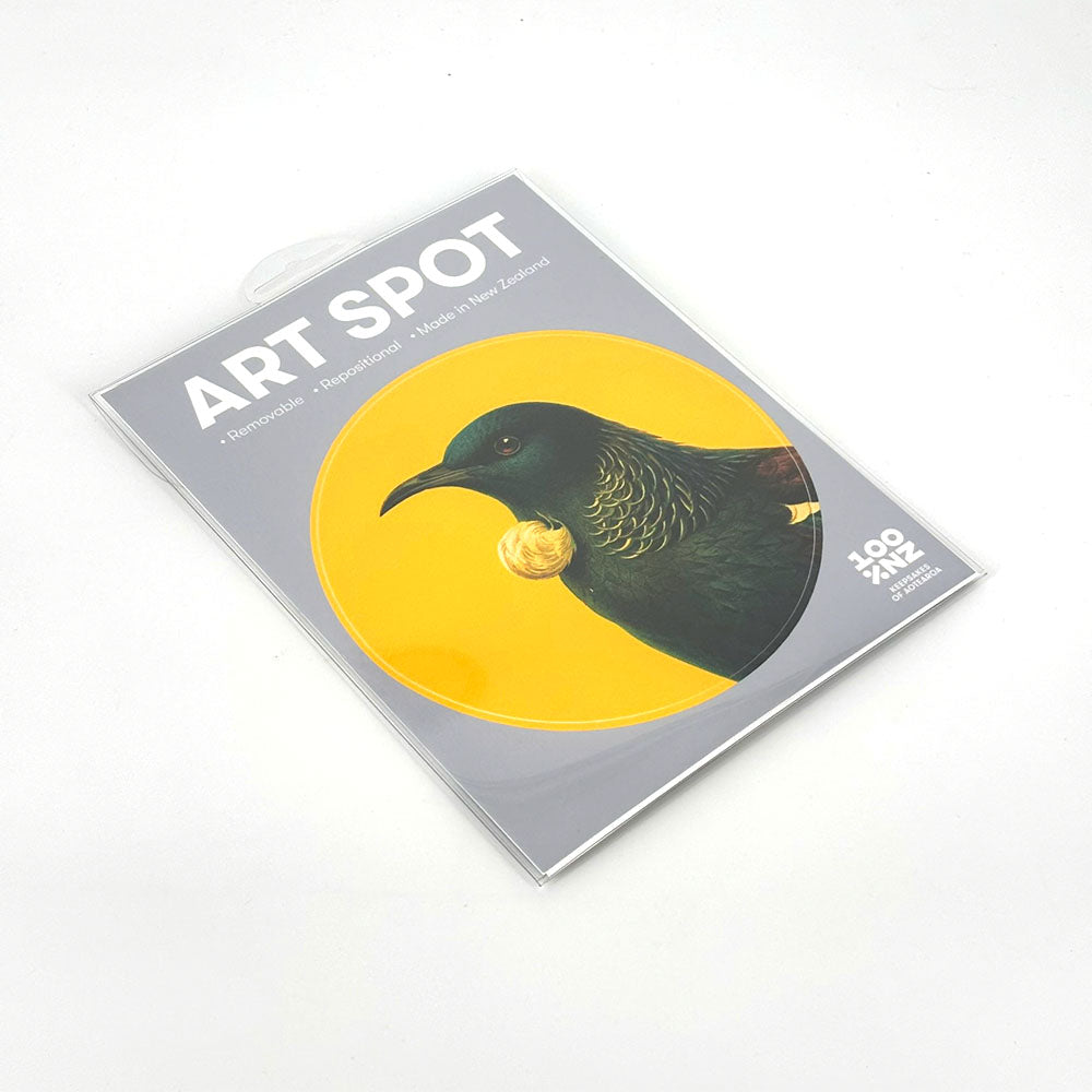 Bright Tui Art Spot is a packaged art print featuring a bird with green and gold plumage on a yellow circle. The peel-and-stick packaging highlights it as removable, repositionable wall art made in New Zealand.