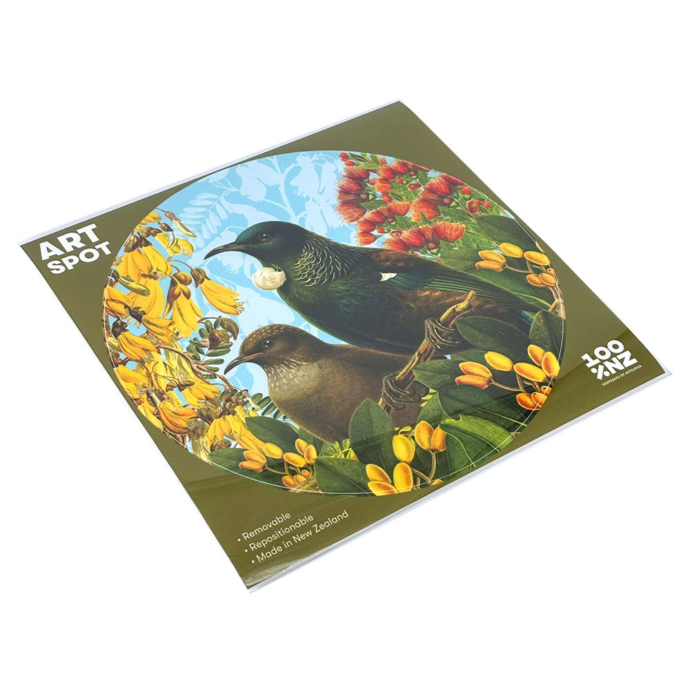 The Botanical Tui Art Spot is a square, repositionable wall art print with a matte fabric finish, featuring two birds among yellow and red flowers, green leaves, and a blue sky. Made in New Zealand.