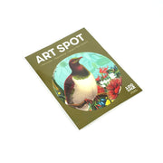A flat, rectangular package labeled Botanical Kereru Art Spot displays an illustrated bird with colorful flowers on an olive green background. The cover features a 100 PIECE PUZZLE logo, text, and notes its matte fabric finish.
