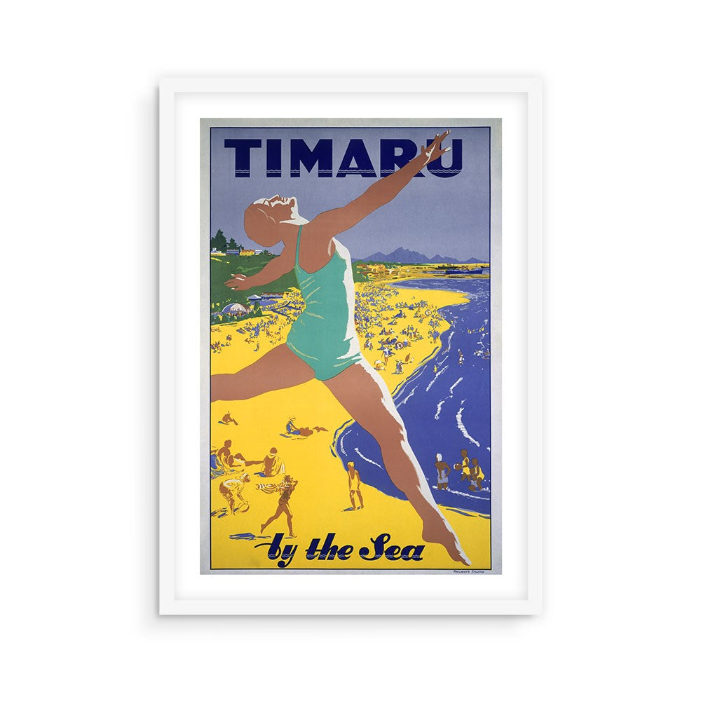 The Timaru Tourist Print showcases a woman in a teal swimsuit leaping on a yellow beach with people behind her. "TIMARU by the Sea" stands out, evoking vintage New Zealand travel posters as an archival print framed in white.