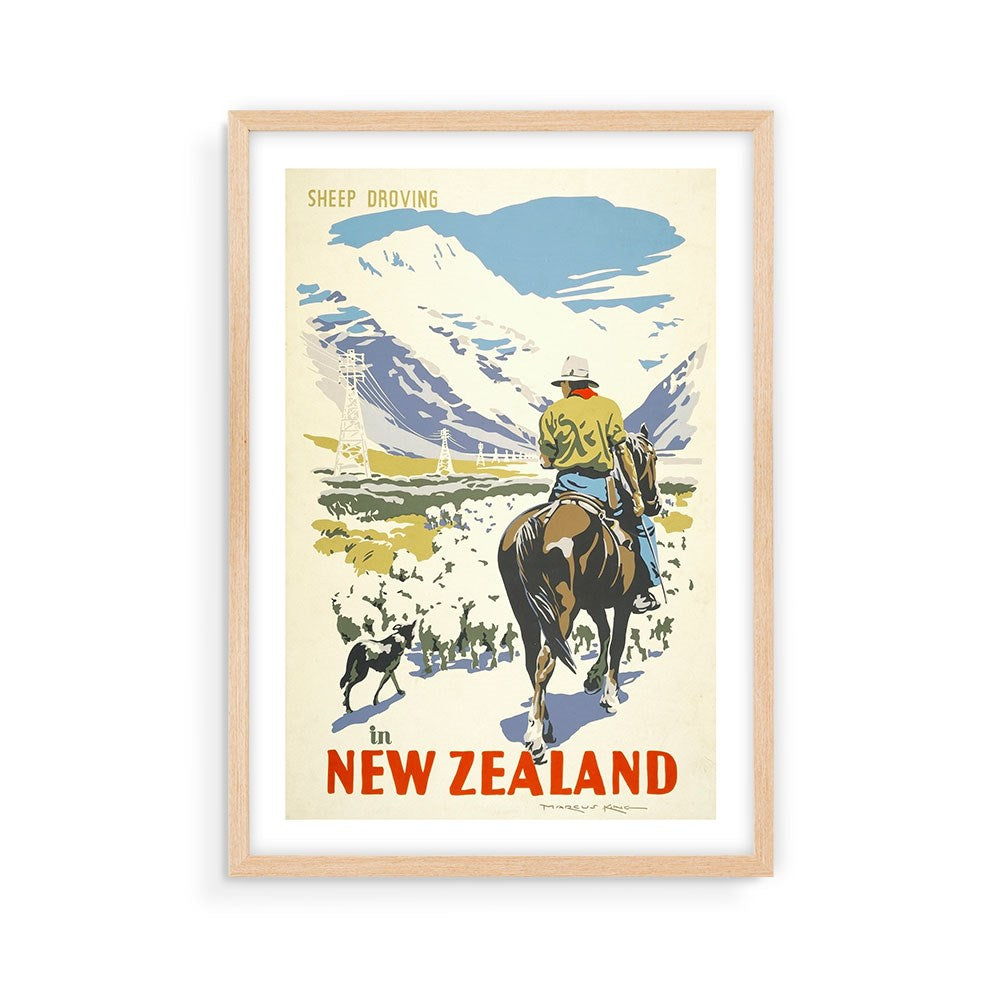 The Sheep Droving Tourist Print is a framed archival vintage poster showing a person on horseback with a dog approaching sheep in New Zealand’s mountains, featuring the text “Sheep Droving in New Zealand.”.