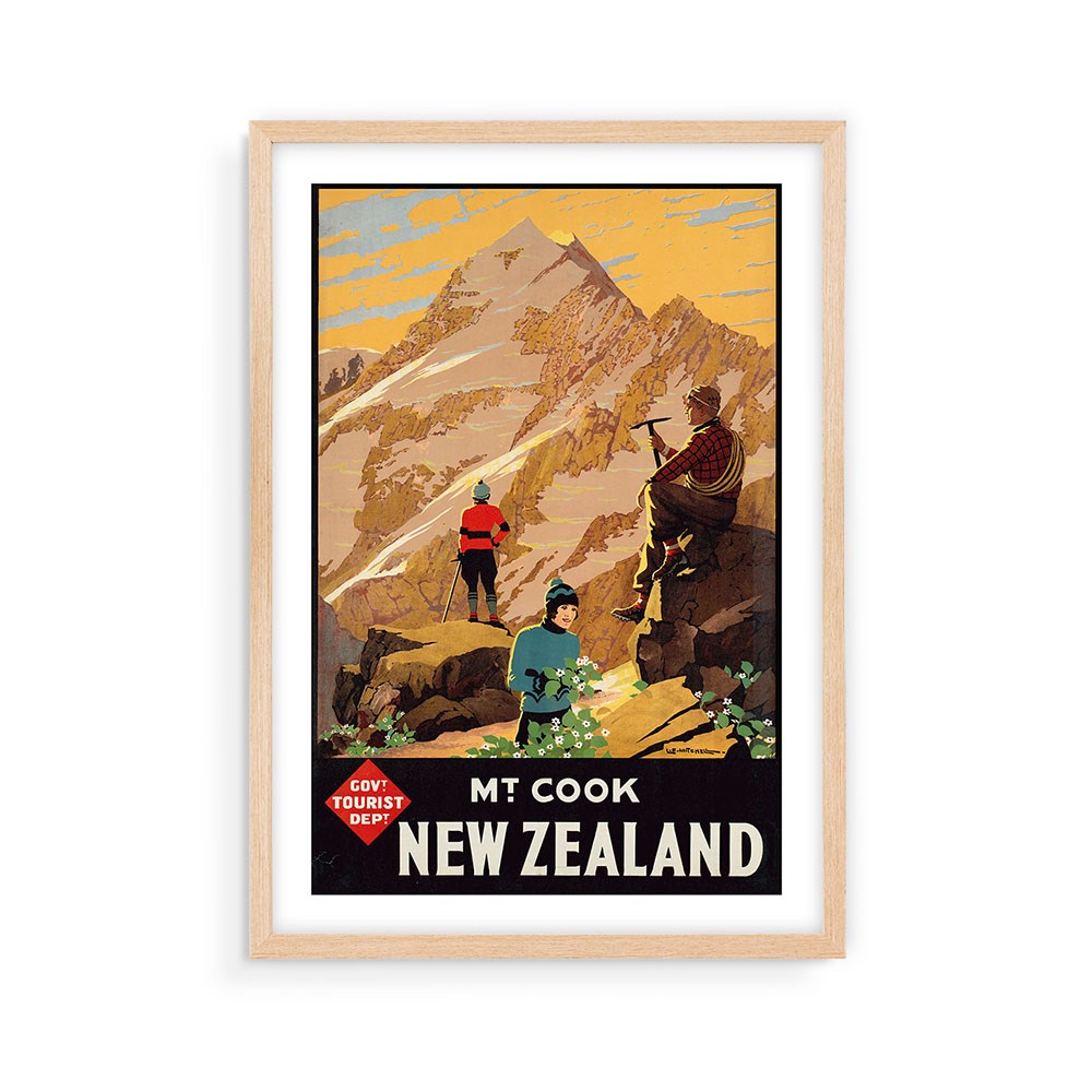 The Mt Cook Tourist Print features three hikers at the rocky base of New Zealands Mt. Cook, with Mt. Cook New Zealand below, framed in light wood—a perfect archival vintage-style poster for any travel lover’s collection.