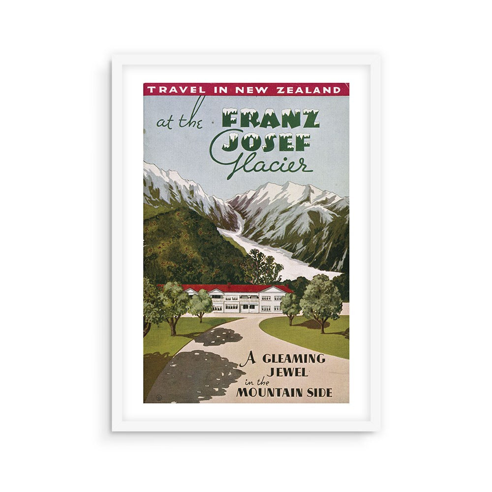 The Franz Josef Glacier Tourist Print features a vintage travel poster of New Zealand's glacier with snow-capped mountains, a foreground lodge, and the phrase "A gleaming jewel in the mountain side," beautifully framed in white.