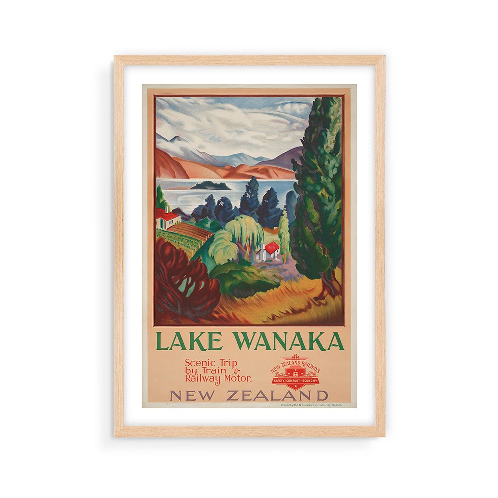 Lake Wanaka Tourist Print: A framed vintage-style archival poster featuring an illustrated landscape of Lake Wanaka with trees, mountains, and buildings. Text reads Lake Wanaka. Scenic trip by train & railway motor. A New Zealand collectible poster.