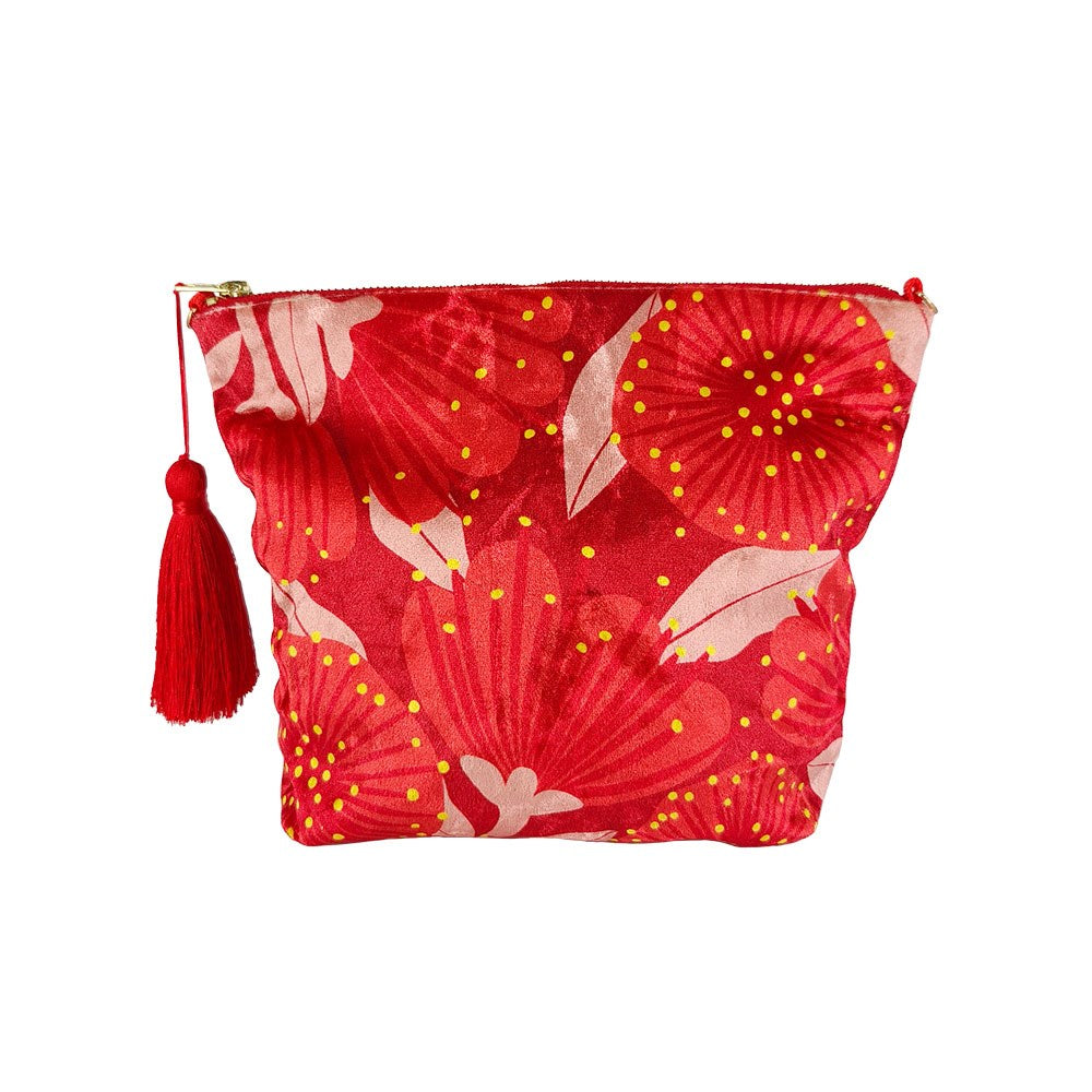 The Bright Botanical Red Pohutukawa Velvet Cosmetic Bag features a zip closure, red and pink floral velvet design inspired by Pohutukawa, yellow dots, and a red tassel on the zipper.