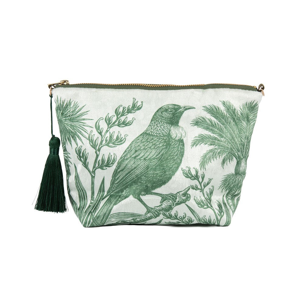 Under the Nikau Velvet Cosmetic Bag is a New Zealand-designed velvet bag featuring a green botanical print with a bird on a branch, leafy trees, and a tassel zipper.