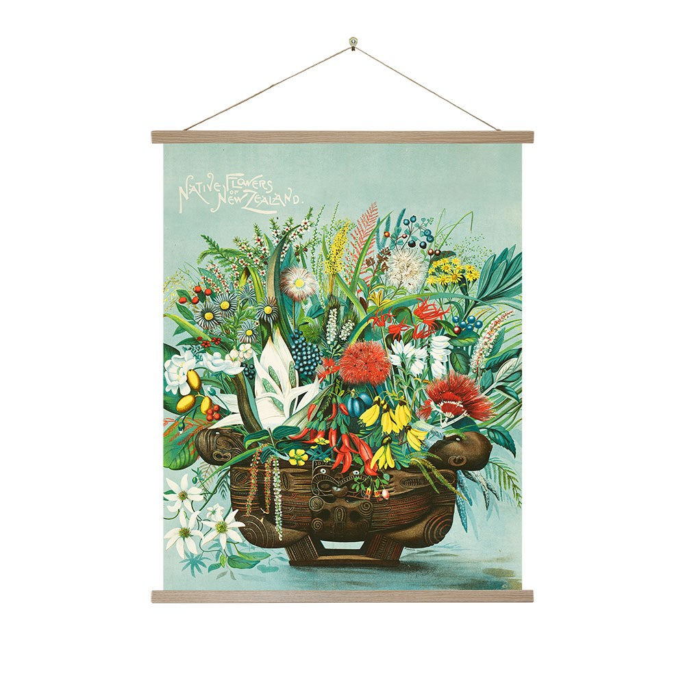 The Native Flowers Wall Chart is a botanical art print of a carved wooden vase with New Zealand native flowers, hung by a string. Native Flowers of New Zealand appears at the top, adding vintage charm to your wall decor.