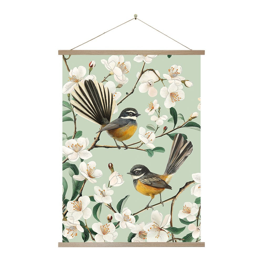 The Chatty Fantails Wall Chart features two yellow and grey fantail birds perched on blossom branches against a pale green background, presented as an instant art hanging wall scroll. Made in New Zealand.