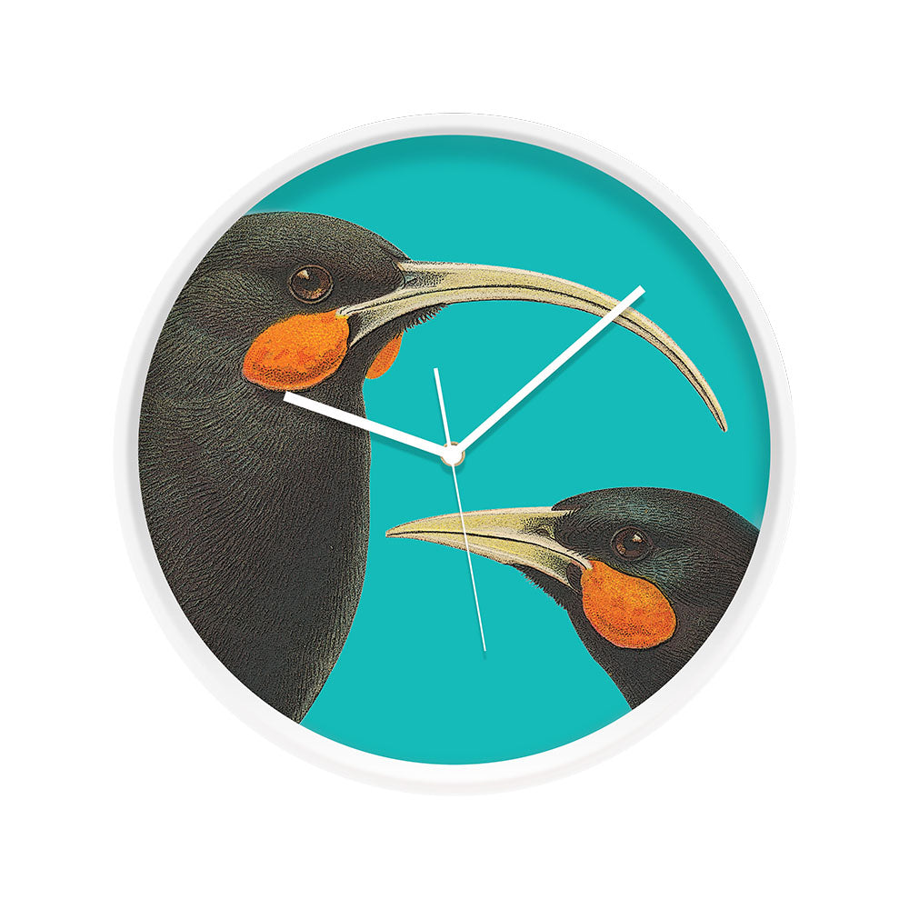 The Bright Huia Wooden Frame Clock features two black huia birds with orange cheeks and curved beaks on a turquoise background. Its silent movement ensures quiet time, all framed in sleek white and round for modern style.