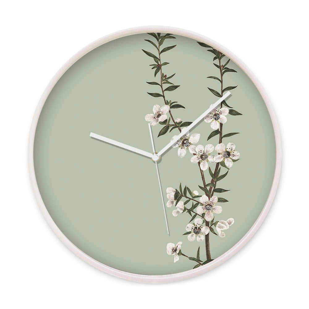 The Vintage Botanical Manuka Wooden Frame Clock features a pale green background with New Zealand native Manuka white flowers, green leaves, and minimalist white hands for a classic touch.