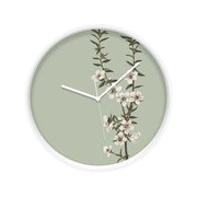 The Vintage Botanical Manuka Wooden Frame Clock - Second features a round wooden frame, pale green face, thin white hands, and a branch with white Manuka flowers and green leaves inspired by New Zealand’s native flora.
