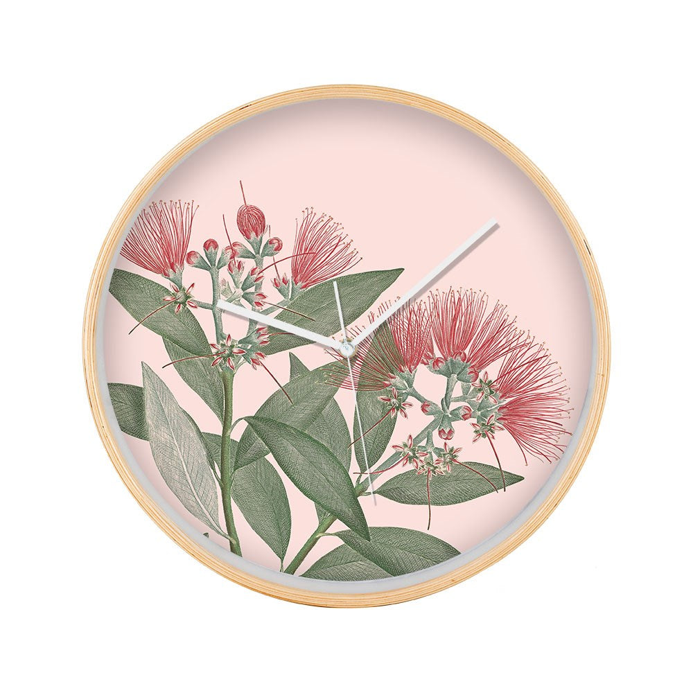 The Vintage Botanical Pohutukawa Wooden Frame Clock features a round wooden frame with an illustration of green leaves and red Pohutukawa flowers on a pale pink background, white hour and minute hands, and no numbers.