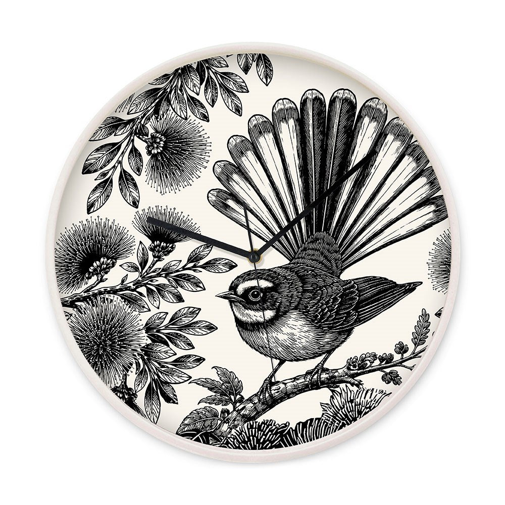 The In Bloom Wooden Frame Clock features a black and white illustration of a NZ Fantail on a branch, surrounded by detailed leaves and flowers. Black clock hands complete this elegant New Zealand wall clock.