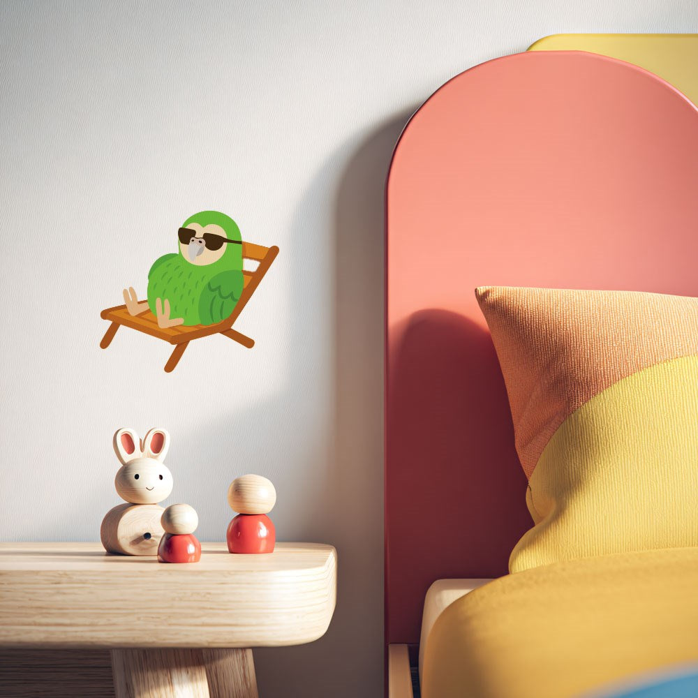 A kids' bedroom with a wooden bunny and peg dolls on a bedside table. On the wall is the Kakapo Wall Decal—a green parrot in sunglasses, lounging on a deck chair. Part of a colorful bed appears in the scene.