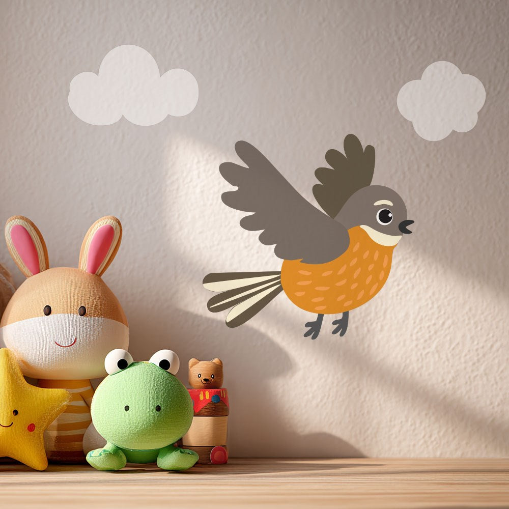 A group of stuffed toys sits on a surface in front of a wall decorated with the Fantail Wall Decal, featuring a cartoon bird and two clouds. Sunlight casts soft shadows across the bunny, green frog, yellow star, and bear.