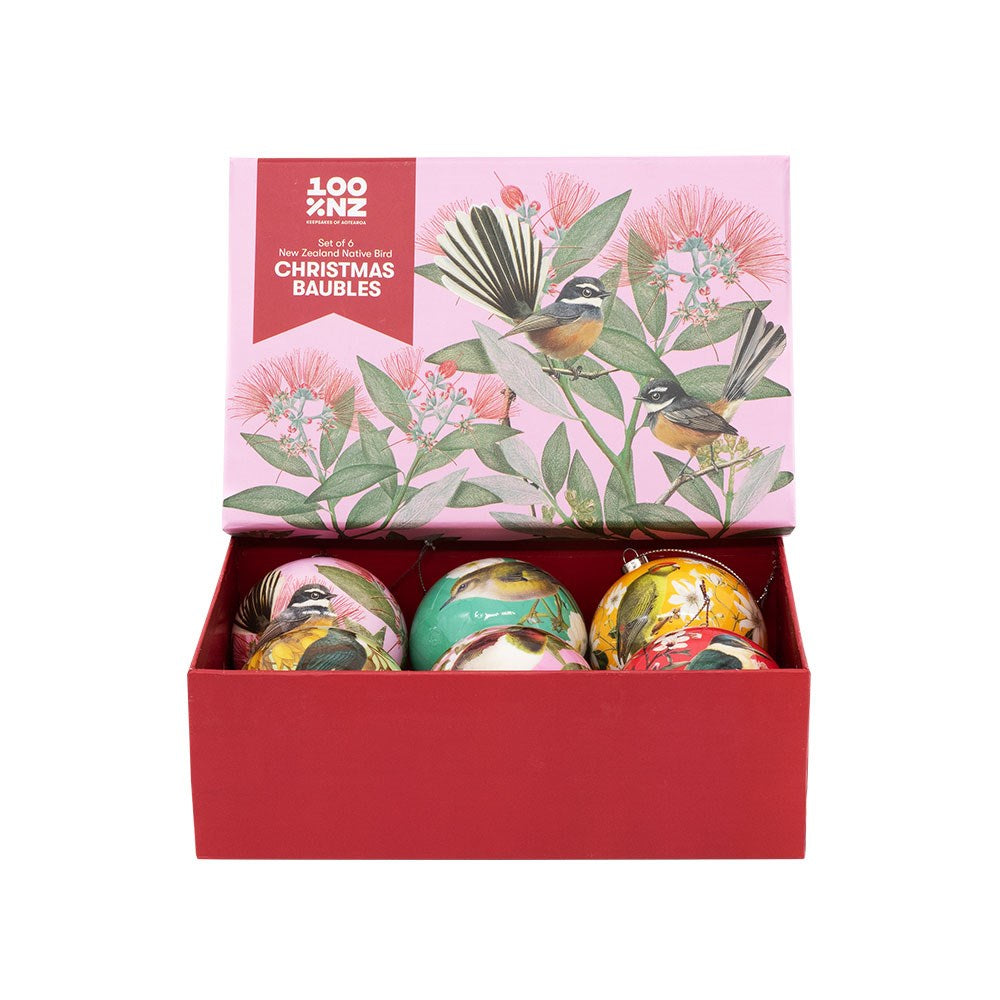 A red gift box set called "NZ Native Birds Christmas Baubles - Second" featuring six colorful Christmas baubles, each adorned with illustrations of New Zealand native birds and floral designs. The open lid of the box displays coordinating artwork and reads "100 NZ Christmas Baubles." Set against a plain white background, these unique decorations beautifully showcase New Zealand’s festive charm.