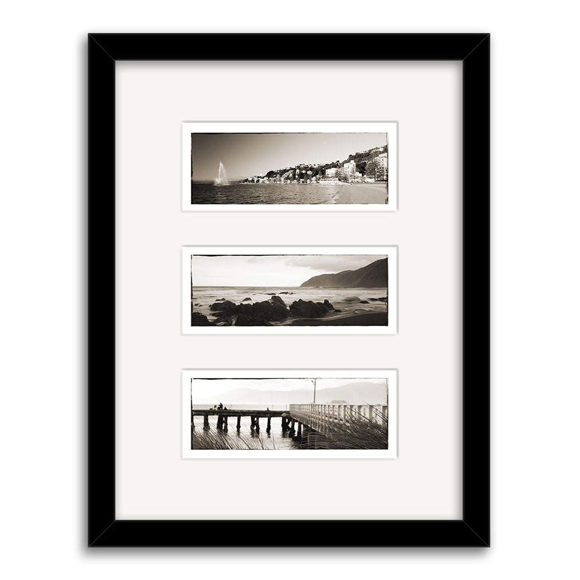 The Wellington Triptych - RP105 features three black-and-white prints by Reuben Price in a black frame with white mats, depicting New Zealand scenes: a coastline, rocky shore, and people on a pier, arranged vertically.