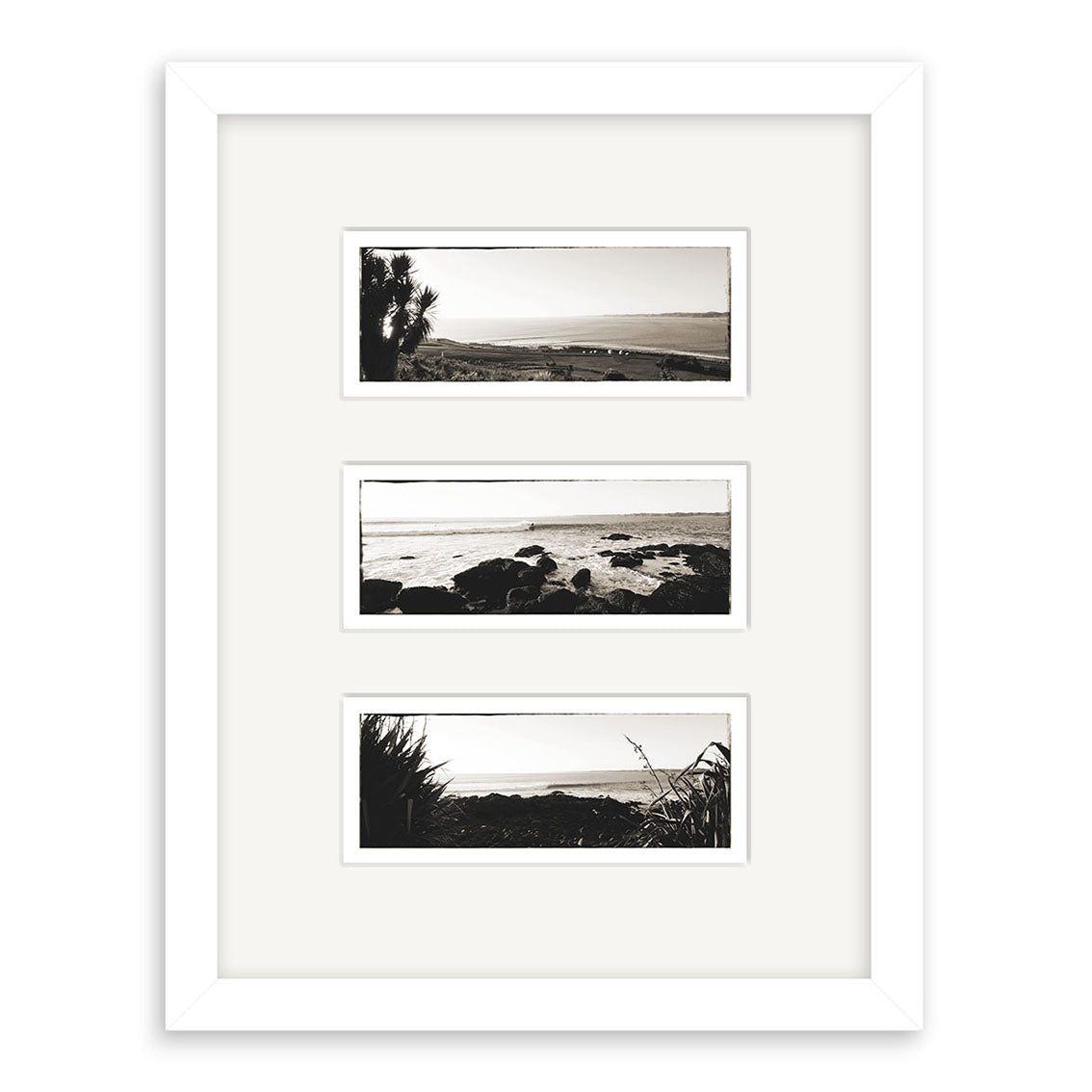 The Raglan Triptych - RP096 features three horizontal black-and-white New Zealand coastal prints with water, rocks, and vegetation, arranged vertically in a white frame with a white mat.