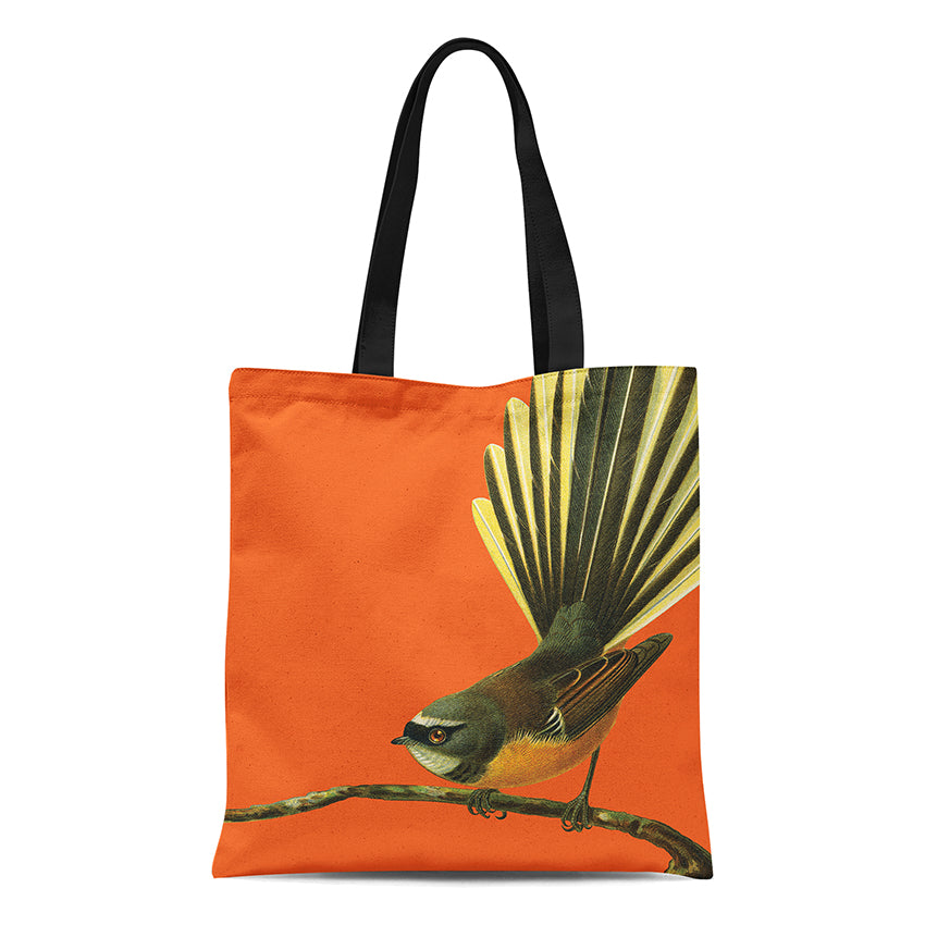 The Bright Fantail Tote Bag is an orange cotton tote with black handles, featuring a colorful bird illustration with a fanned tail on a branch—perfect for adding summer charm to any outfit.