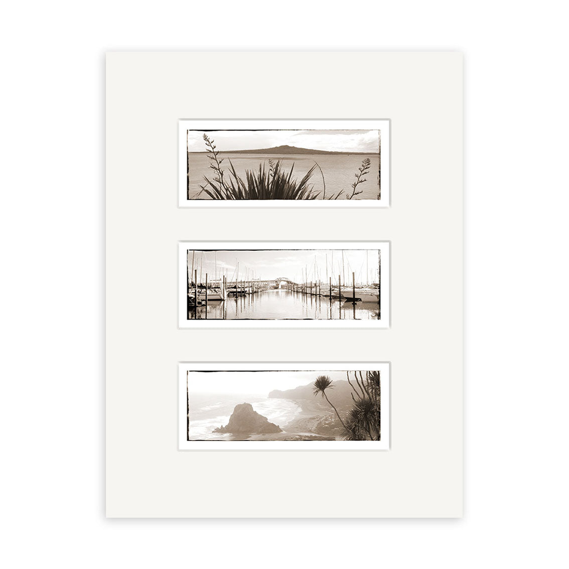 The Auckland Triptych - RP004 is a white-matted set of three archival sepia photographic prints showing New Zealand landscapes: a plant-lined coastline, a sailboat marina, and a rocky shore with foliage.