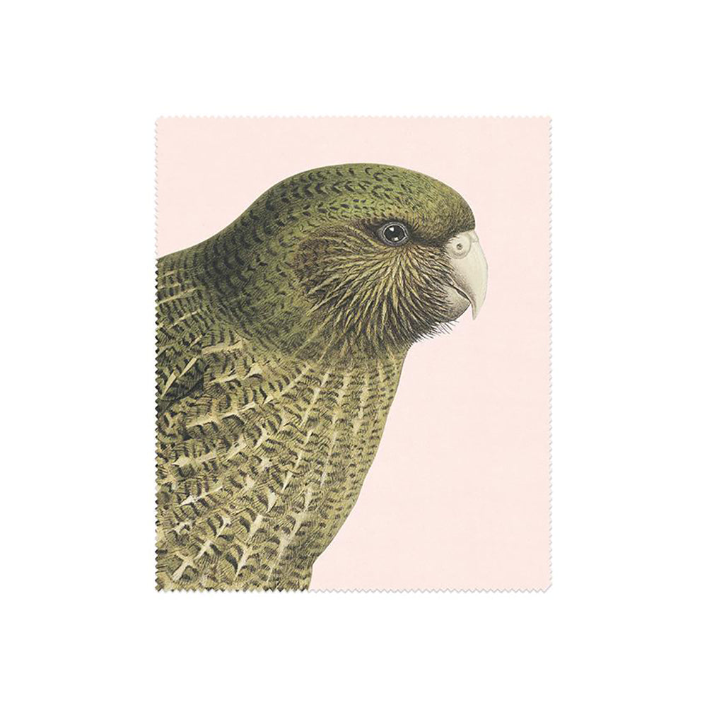This rectangular lens cloth from the Set of 3 Hushed Collection Lens Cloths features a green parrot with detailed feathers and a white beak on a pale pink background, finished with zigzag edges.
